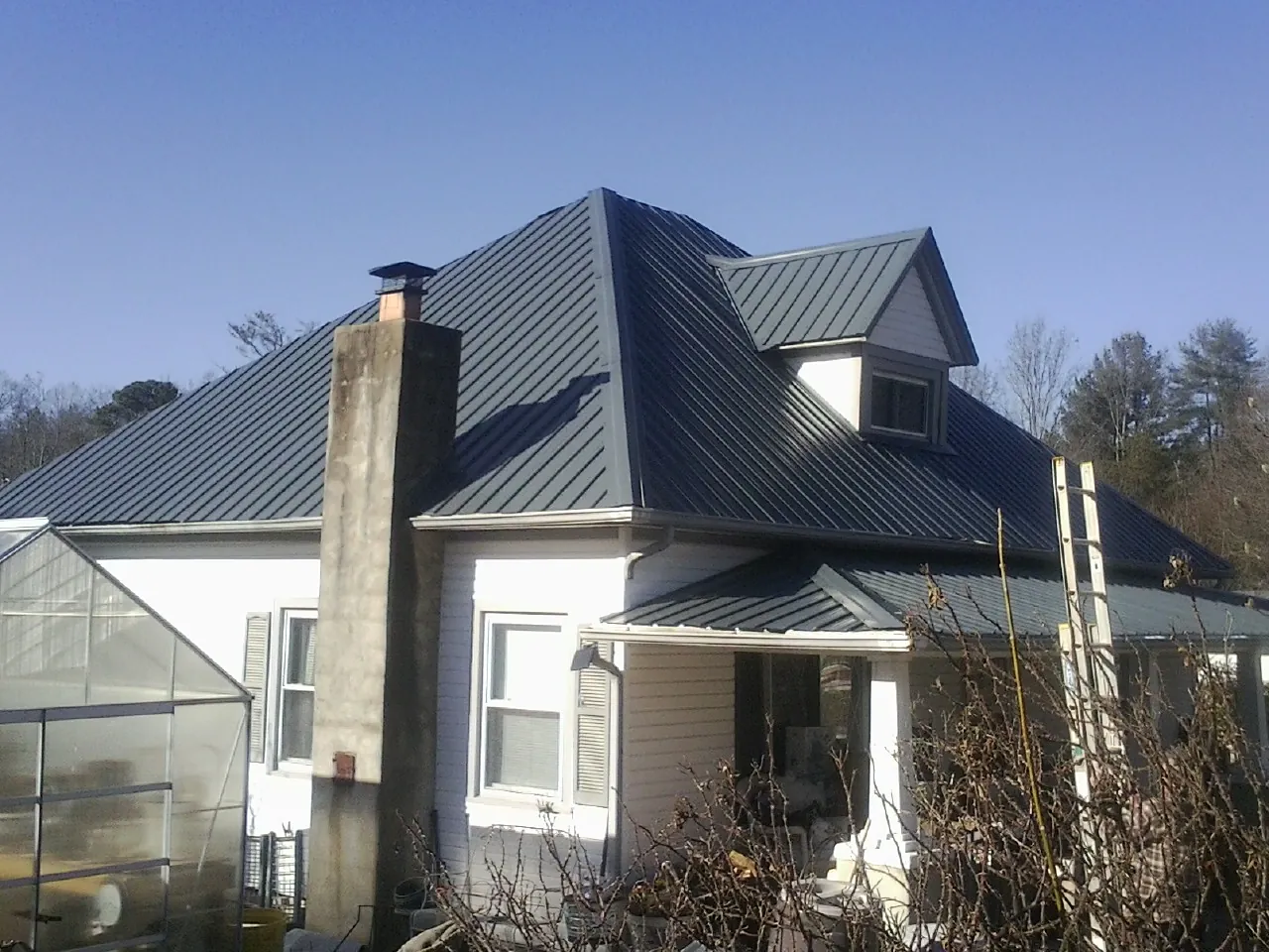 Dark blue standing seam metal roof on a white farmhouse with dormer — Slate & Tile Roof Repair by Roofing Brothers in Seymour
