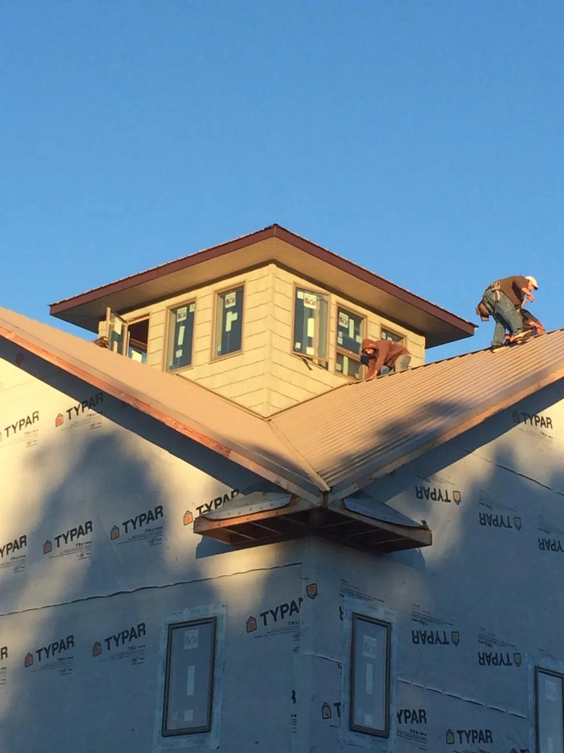 Roofers working around a rooftop cupola on a new metal roof at sunset — Roof Waterproofing in Seymour by Roofing Brothers